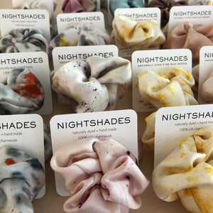 Group of silk hair scrunchies on display with Nightshades cards